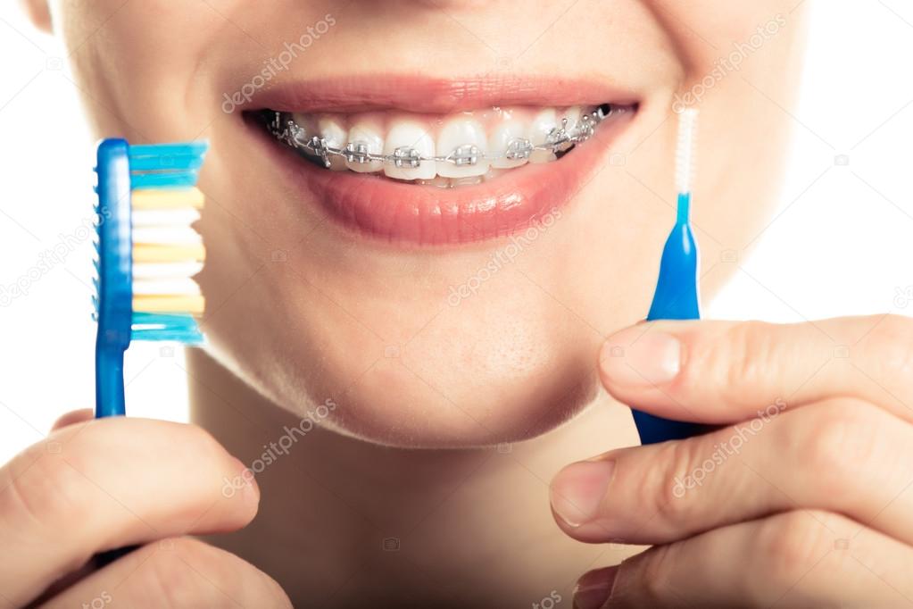 Beautiful smiling girl with retainer for teeth brushing teeth.
