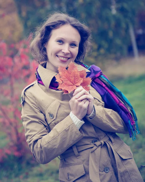 Schönes Mädchen mit einem Ahornblatt in der Hand. — Stockfoto