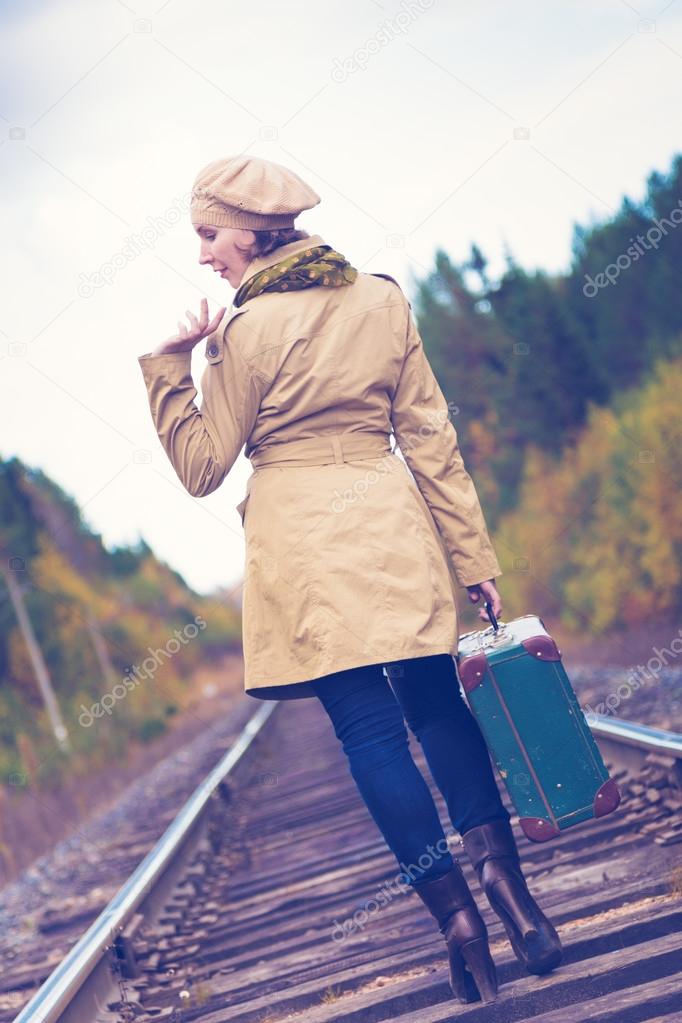 Elegant woman with a suitcase traveling by rail.