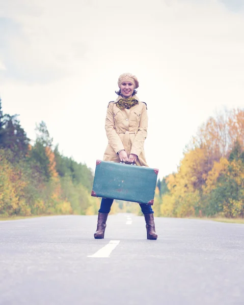 Elegant kvinna med en resväska reser motorvägen. — Stockfoto