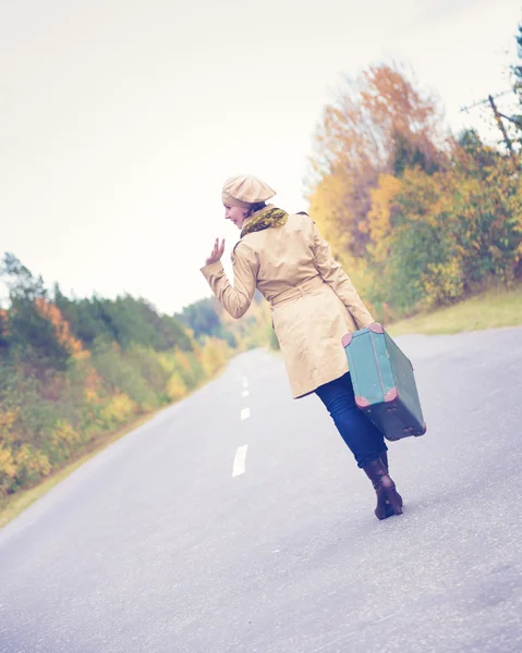 Elegancka kobieta z walizką podróżujących autostradą. — Zdjęcie stockowe