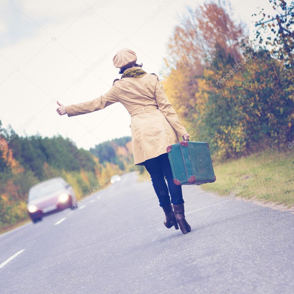 Elegant woman with a suitcase traveling the highway.