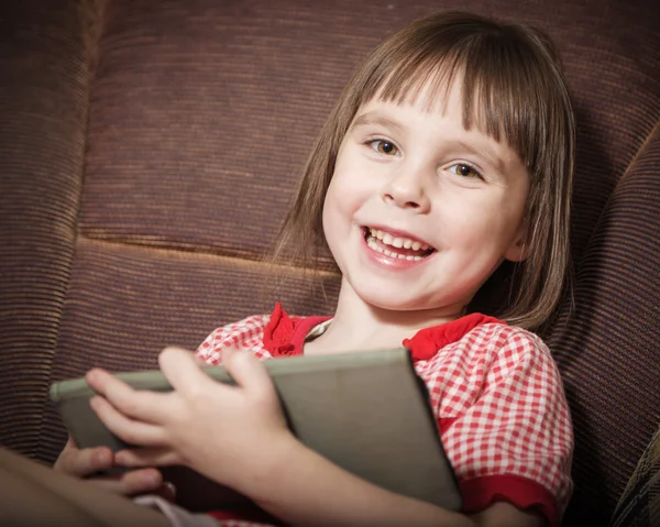 Kleines Mädchen spielt mit einem modernen digitalen Tablet. — Stockfoto