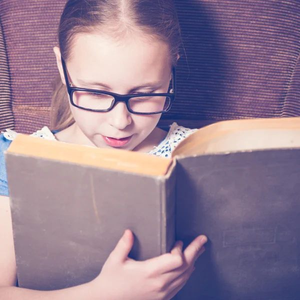 Chica leyendo un libro en casa sentada en un sillón . —  Fotos de Stock