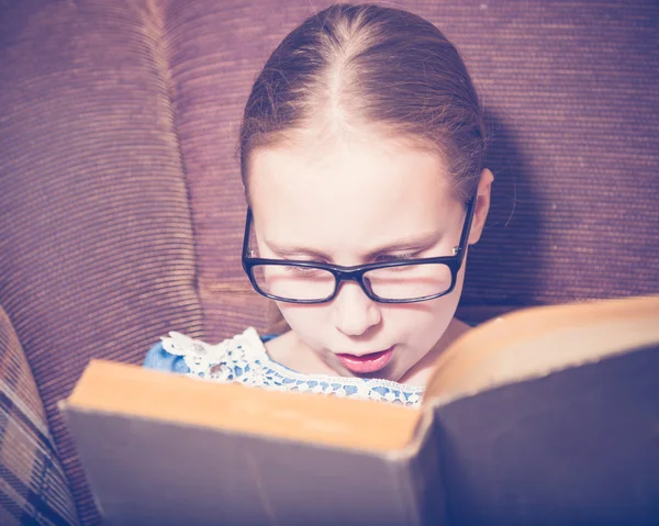 Meisje het lezen van een boek thuis zitten in een leunstoel. — Stockfoto