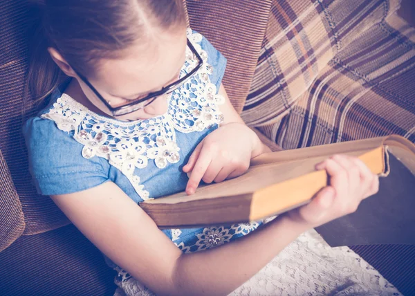 Meisje het lezen van een boek thuis zitten in een leunstoel. — Stockfoto