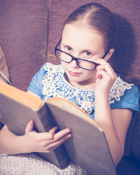 Dziewczyna czytając książkę w domu siedzi na fotelu. — Zdjęcie stockowe