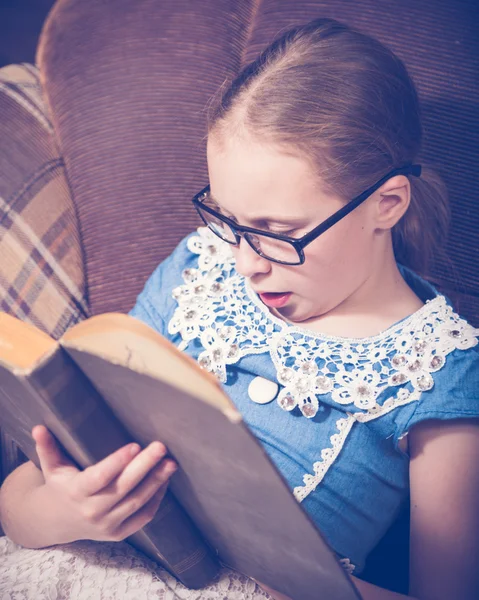 Chica leyendo un libro en casa sentada en un sillón . —  Fotos de Stock