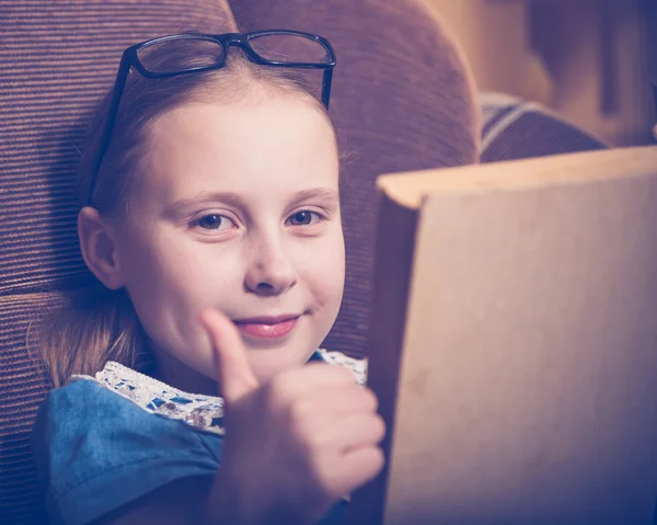 Menina lendo um livro em casa sentado em uma poltrona . — Fotografia de Stock