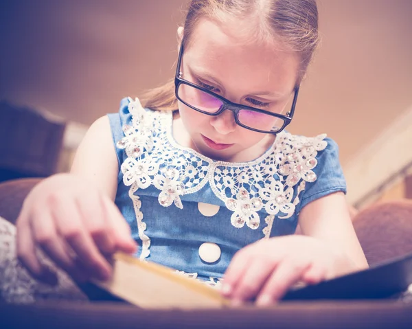 Meisje het lezen van een boek thuis zitten in een leunstoel. — Stockfoto
