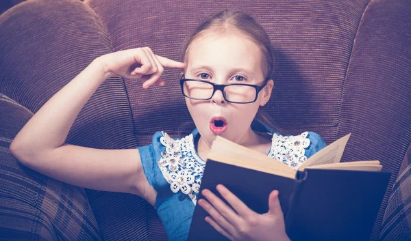 Meisje het lezen van een boek thuis zitten in een leunstoel. — Stockfoto