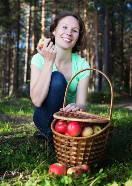 Vacker kvinna med en korg full av äpplen . — Stockfoto