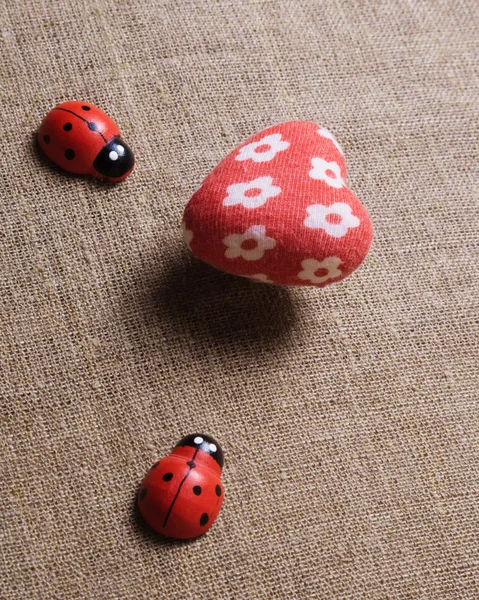 Cuore e coccinella sul tessuto . — Foto Stock