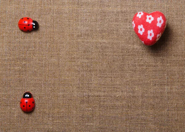 Cuore e coccinella sul tessuto . — Foto Stock