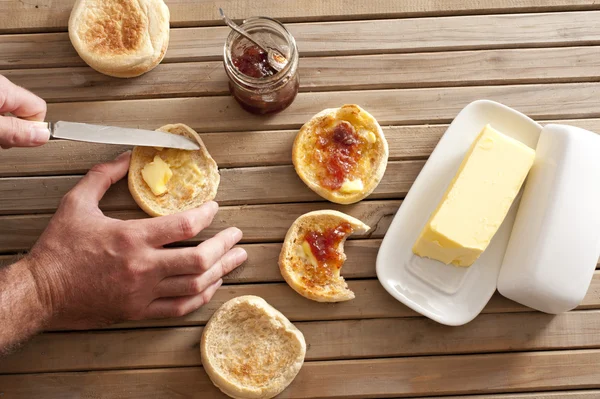 Man buttering a crumpet for breakfast — Stock Photo, Image