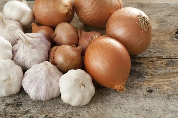 Sklizeň čerstvé cibule a česnek na dřevo stůl — Stock fotografie