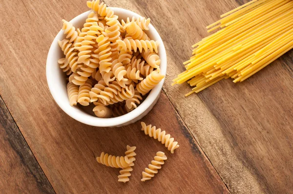 Massas Secas Espiral Italiana Fusilli Espaguete Uma Mesa Cozinha Madeira — Fotografia de Stock