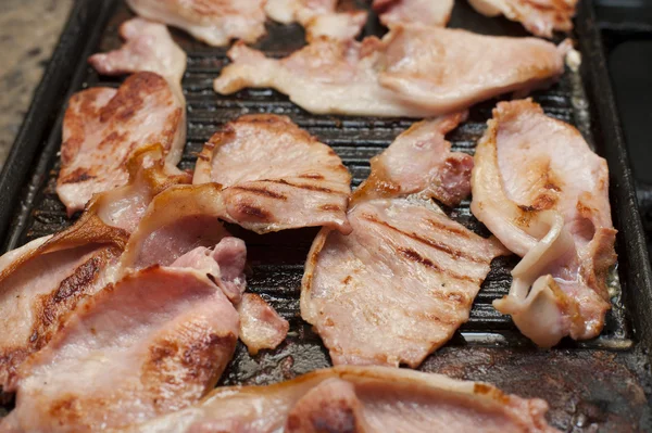 Rashers of smoked bacon on a griddle — Stock Photo, Image