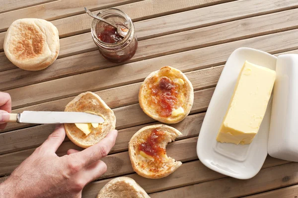 Man buttering a fresh crumpet for breakfast — Stock Photo, Image