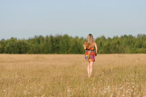 Jovem mulher caminha no campo — Fotografia de Stock