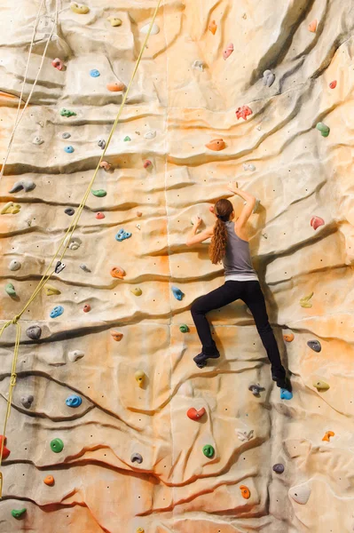 Frau klettert auf künstliche Klippe — Stockfoto