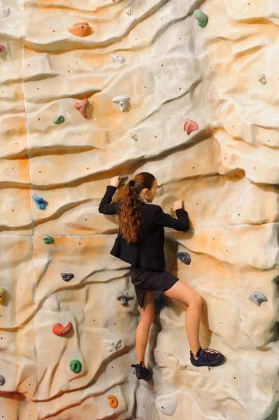 Businesswoman climbing on man-made cliff — Stock Photo, Image