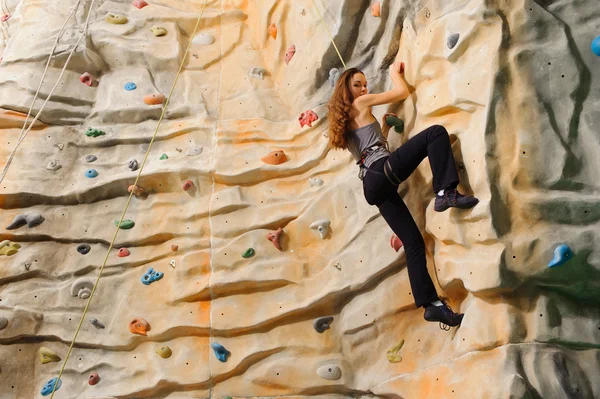 Femme grimpant sur une falaise artificielle — Photo