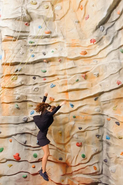 Businesswoman climbing on man-made cliff — Stock Photo, Image