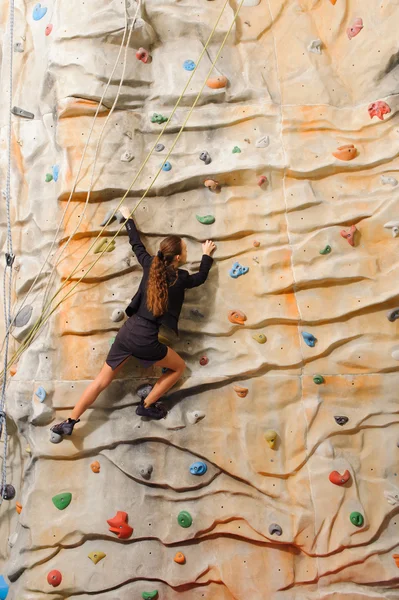 Businesswoman climbing on man-made cliff — Stock Photo, Image