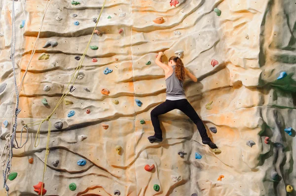 Frau klettert auf künstliche Klippe — Stockfoto