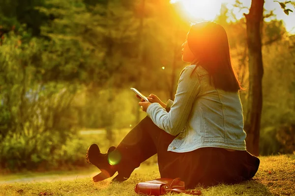 Donna seduta nel parco con cellulare — Foto Stock