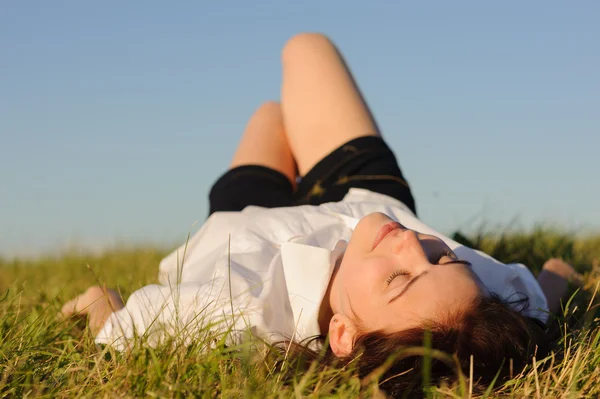 Vrouw liggend op het groene gras — Stockfoto