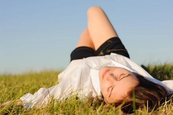 Vrouw liggend op het groene gras — Stockfoto