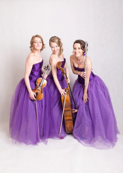 Musikalisches Trio in lila Kleidern — Stockfoto