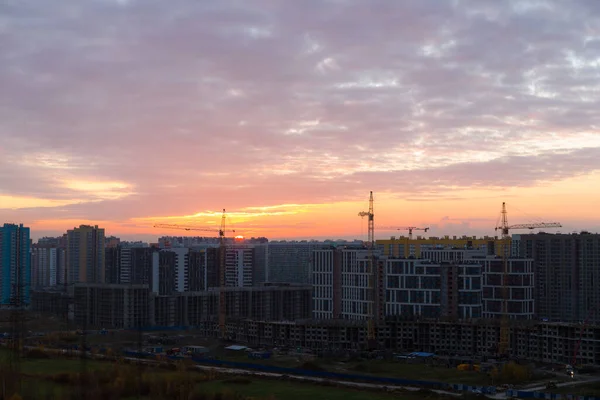 街と建設現場の上の明るい夕日 — ストック写真