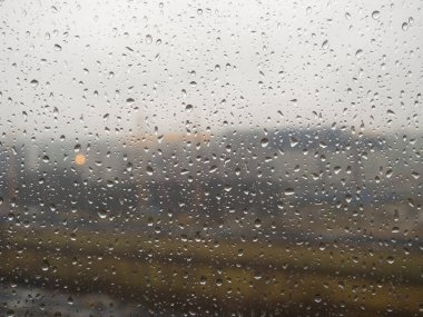 Pencerenin dışındaki şehir Bulutlu bir günde yağmur damlalarıyla