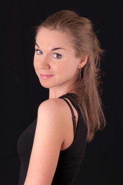 Siyah arka planda gülümseyen bir kızın stüdyo portresi.