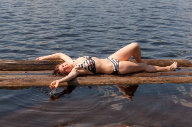 Bikinili kız yaz gölünde salda yatıyor.