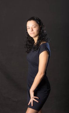 Siyah arka planda elbise giymiş bir kızın stüdyo portresi.