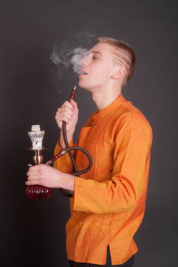 Siyah arka planda nargilesi olan bir adamın stüdyo portresi.
