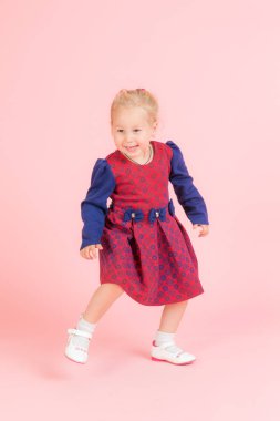 Pembe arka planda dans eden bir kızın stüdyo portresi.