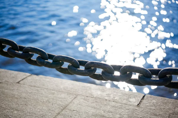 Cadena en el muelle en el fondo brillante en el agua del sol — Foto de Stock