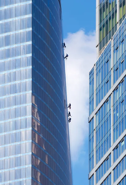 Vedligeholdelsesarbejdere klatrer op ad ydermuren af en skyskraber - Stock-foto