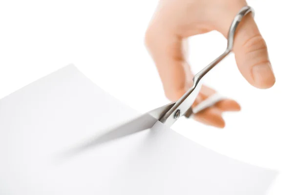 Hand met een schaar een wit vel papier snijden — Stockfoto