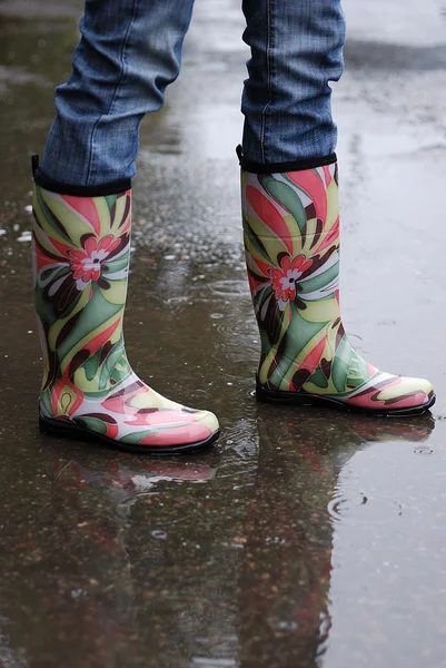 Woman's Legs Wearing Rainboots in Puddle