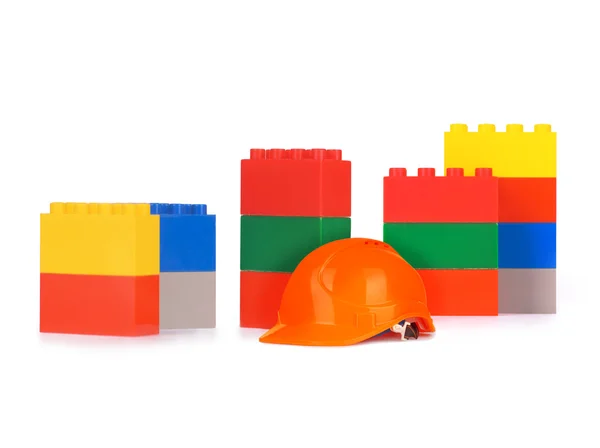 Byggstenar leksak med hjälm på vit — Stockfoto