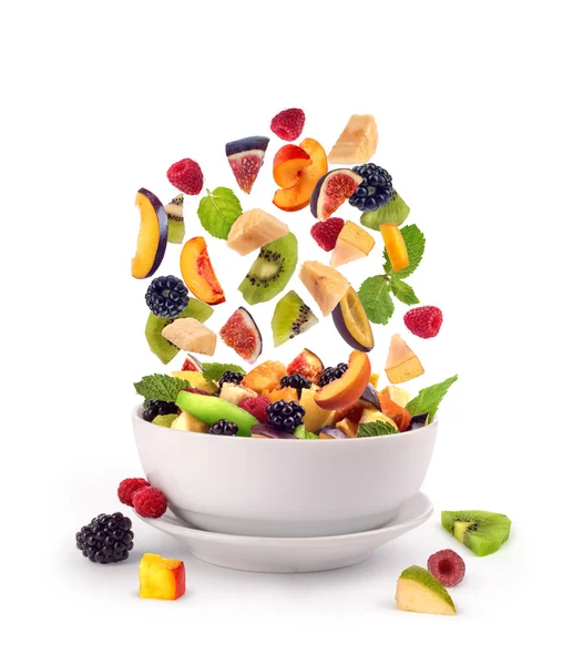 Pedaços de frutas frescas misturadas caindo em tigela branca de salada de frutas — Fotografia de Stock