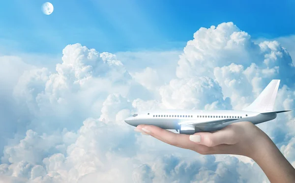 Travel concept. A human hand holds an airplane in the clouds. 3d illustration.