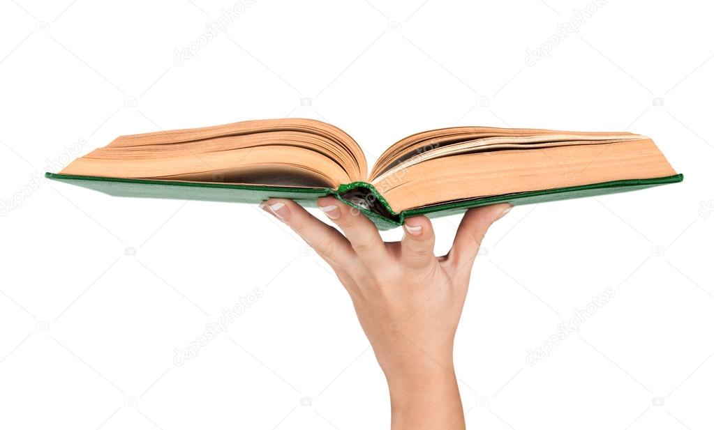 Female hand holding an open vintage book in green cover. Concept