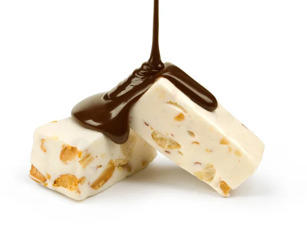 Liquid caramel runs down the candy nougat and nuts on a white background isolation — Stock Photo, Image